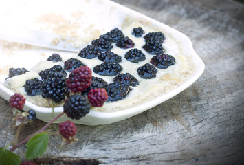Dessert with blackberries in a plate with knife isolated on wooden background