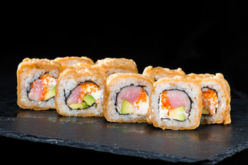 Traditional Japanese cuisine. Selective focus on sushi rolls with salmon, cream cheese, rice, cucumber, caviar and raw meat on dark background
