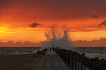 wave hits the pier at sunset in nr. Vorupoer at the North Sea Coast in Denmark