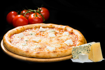 selective focus on appetizing Italian cheese pizza with mozzarella, gorgonzola, emmental and parmesan cheese on wooden round board on dark background