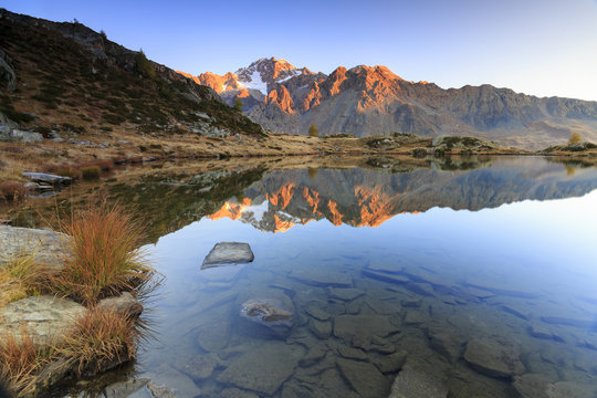 Rocky peaks of Mount Disgrazia reflected in Lake Zana at sunrise, Malenco Valley, Valtellina, Lombardy