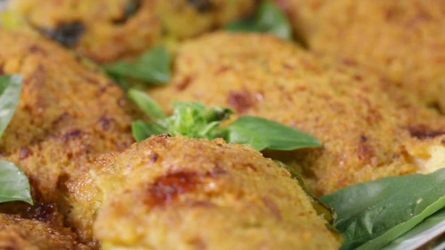Crocchette di zucchine e mollica di pane con basilico fresco in un piatto rotante.