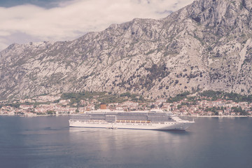 Cruise liner in a bay on the background of mountains. Toned