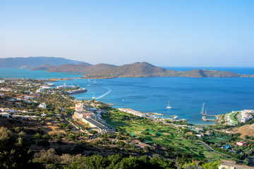 Fototapeta na wymiar Panoramic view of the gulf of Elounda with the famous village of Elounda and the island of Spinalonga at sunset with nice clouds and calm sea, Crete, Greece.