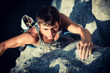 Men climbs a rock and find next holds on a rock