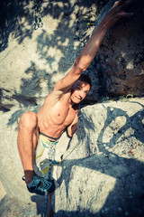 Men climbs a rock and makes hard move, bouldering