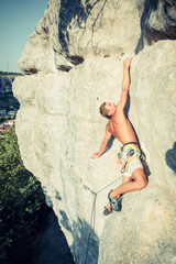 Men climbs an overhanging rock and landscape on the background