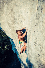 Men climbs an overhanging rock and forest  on the background
