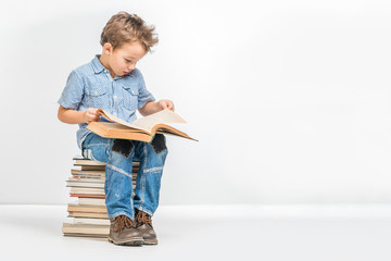 Cute boy in a blue shirt reading a book on a white background
