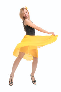 Beautiful young blonde girl in a black top, a yellow skirt and black high heel shoes dancing