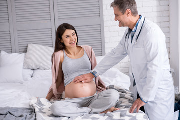 Fototapeta premium Positive delighted pregnancy looking at her doc