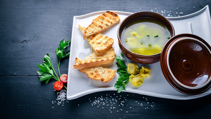 Broth from ravioli and herbs. Italian cuisine. On a wooden background. Top view. Free space for your text.