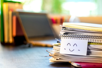 Smile Icon; Stack of Documents and Laptop at working Desk.