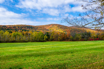 Fototapeta premium Beautiful Mountain Landscape with Meadow in Foreground under Blue Sky with Clouds on an Autumn Morning