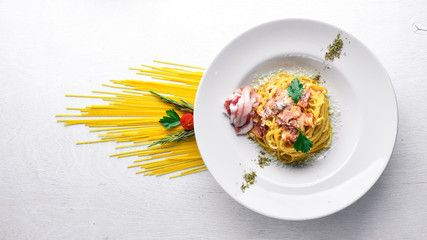 Pasta with bacon in creamy sauce. Italian traditional food. On a wooden background. Top view. Free space for your text.