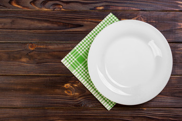 Empty plate and towel over wooden table background. View from above with copy space