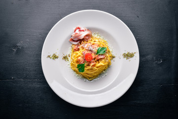 Pasta with bacon in creamy sauce. Italian traditional food. On a wooden background. Top view. Free space for your text.