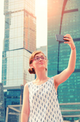 Young girl  taking picture selfie against skyscrapers background