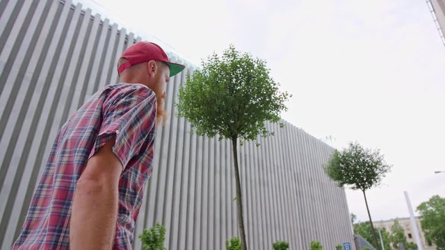 Young readhead hispter with beard and moustaches in jeans and shirt walks the street. Outdoor. Cloudy. Medium. Stabilised.