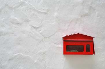 Old red mailbox mounted on a cement wall with copy space.