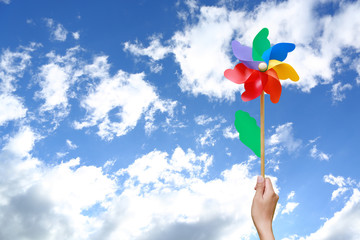 Hand holding pinwheel against sky with copy space.