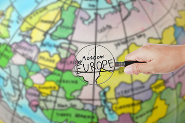 Magnifying glass on hand against globe map background, Focus at Europe.