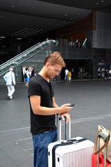 Handsome young man traveling and looking at his mobile phone.