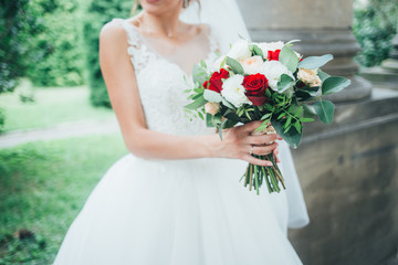 Young beautiful bride holds a bouquet in her hands