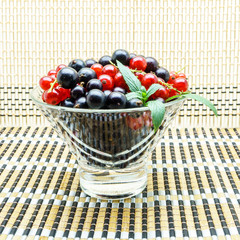 Glass vase with black and red currant