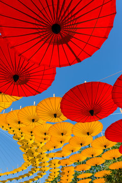 Colorful Thai traditional handmade umbrellas as space decoration on blue sky background