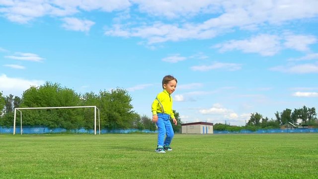 Boy child kicks a soccer ball on the background of a football goal