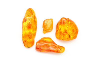 Fototapeta na wymiar Amber. Bright yellow pieces of amber on a white background. Sunstone as a precious stone. Mineral for jewelry. Vintage ancient resin. Baltic amber. Colored bright pieces of amber resin. Top view