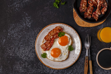 Breakfast with bacon , fried egg, coffee and orange juice.
