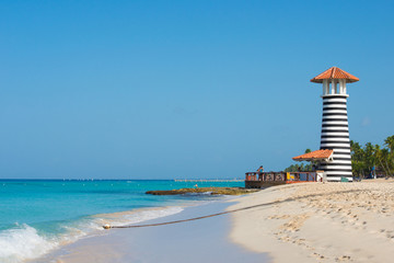 Fototapeta premium Striped red white lighthouse on the coast of the Caribbean Sea. Dominican Republic.