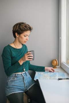 Young woman drinking coffee while looking at map