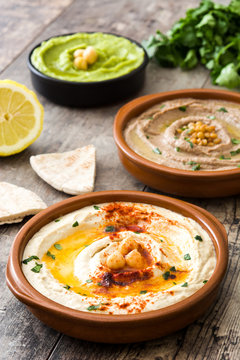 Different hummus bowls. Chickpea hummus, avocado hummus and lentils hummus on wooden table

