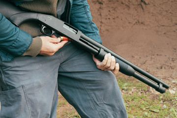 A man loading a 12 bore cartridge in a pump action shotgun