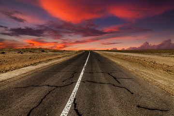 Picturesque fiery sunset over the cracked desert road