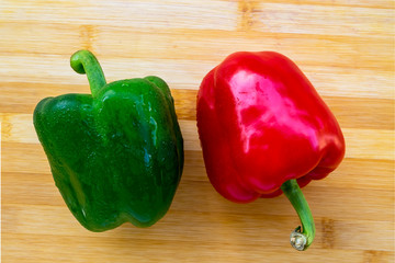 Red and green bell pepper on wooden table, top view with copy space