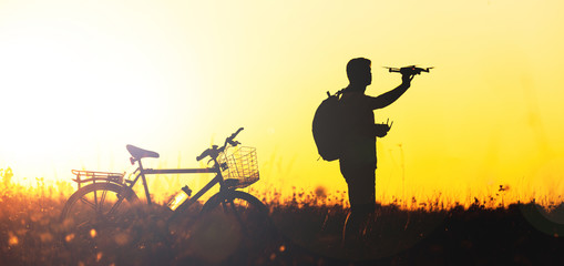Obraz premium Young man operating of flying drone the setting sun