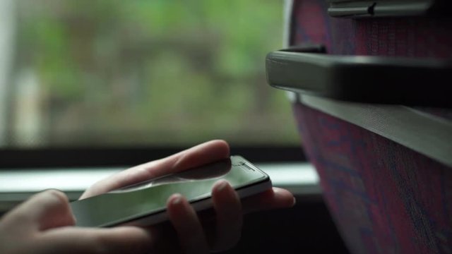 Close up of female hand browsing photos on smartphone during bus ride
