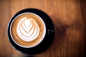 Latte art on dark grained wood top view