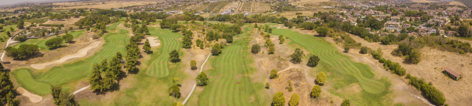 Ampia vista aerea panoramica su un circolo da golf molto grande e ricco di verde. Ci sono ostacoli sabbiosi e alberi in modo da complicare il gioco agli sportivi.