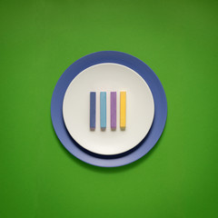 Dinner is served / Creative concept photo of kitchenware, painted plate with food on it on green background.