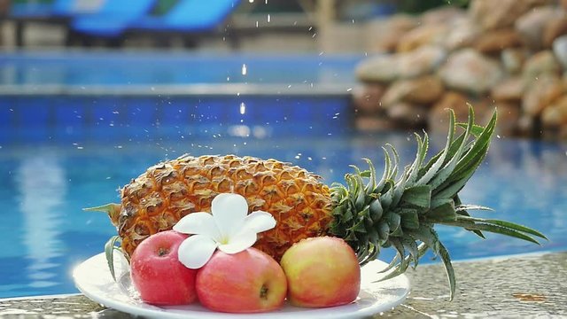 A splash of water on a fruits Pineapple and Rose Apple and frangipani flower on the back of Swimming Pool in slow motion. Fresh Breakfast in Thailand. 1920x1080