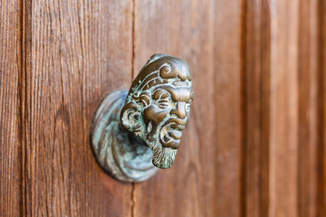 Demon. Ancient door knob on a wooden door in Venice, Italy. Filtered image, old lens effect applied, also grunge and vignette