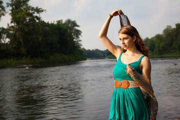 Fototapeta na wymiar Beautiful Girl holding scarf by water's edge