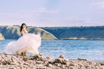 Gorgeous bride in luxury white dress spinning around on a beauti