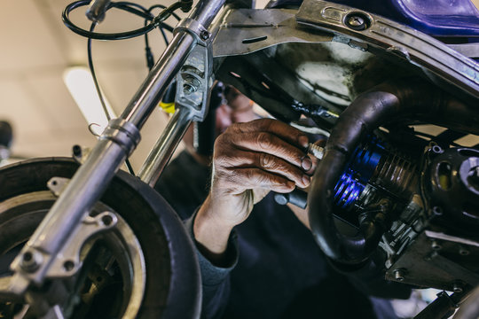 Mechanical Operator Changing a Mini Bike Spark Plug