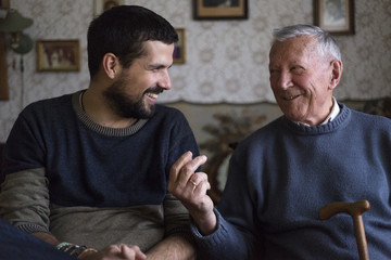 Grandpa and his grandson sitting at the table talking and laughing